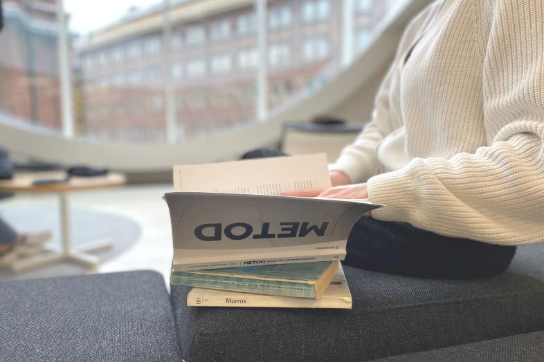 En person bläddrar i böcker på en bänk i Kajsahuset.