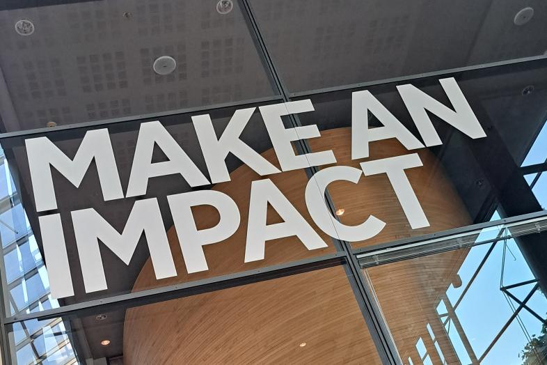 Lasiseinä, jossa teksti "Make an impact".