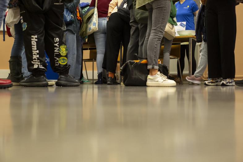 Joukko opiskelijoita seisoo luentosalissa.