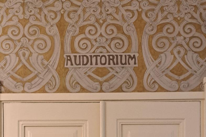 Oven yläpuolella vanha, koristeellinen tapetti, jossa teksti "Auditorium".