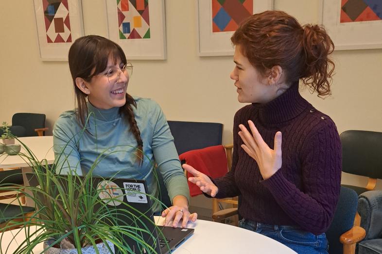 Two people sitting discussing in front of a laptop.