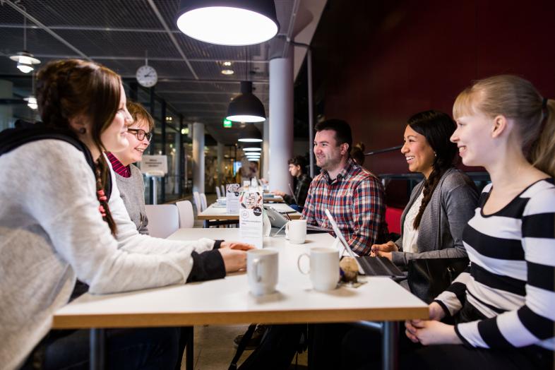 Människor som pratar runt ett kaffebord.