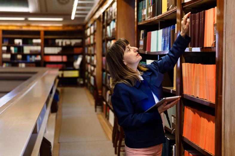 Tutkija Kansalliskirjaston hyllyjen ääressä.