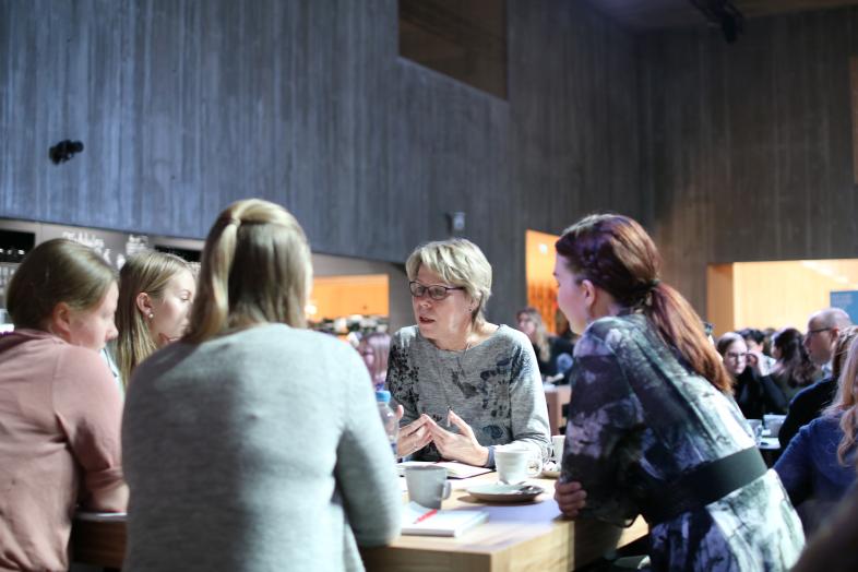 Viisi henkilöä keskustelee pöydän ääressä Tiedekulmassa.