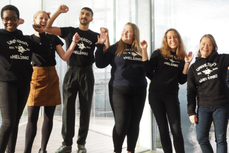 En grupp av glad avseende människör inför fönstret av Oodi bibliotek