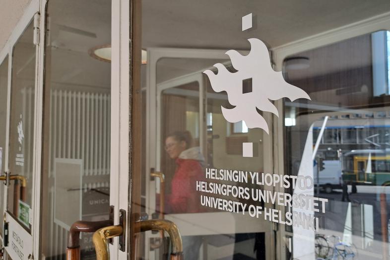 På glasdörren finns universitetets flammärke och texten ”Helsingfors universitet” på tre språk.