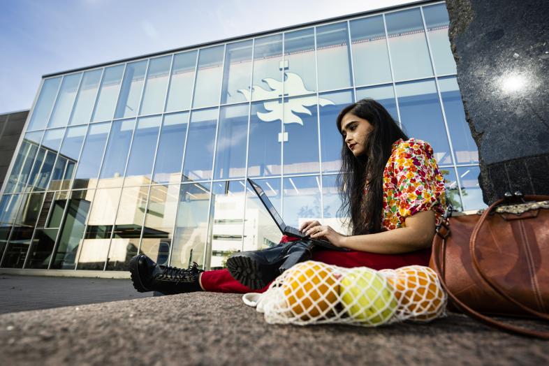 Nainen tietokoneella Kumpulan kampuksen edessä