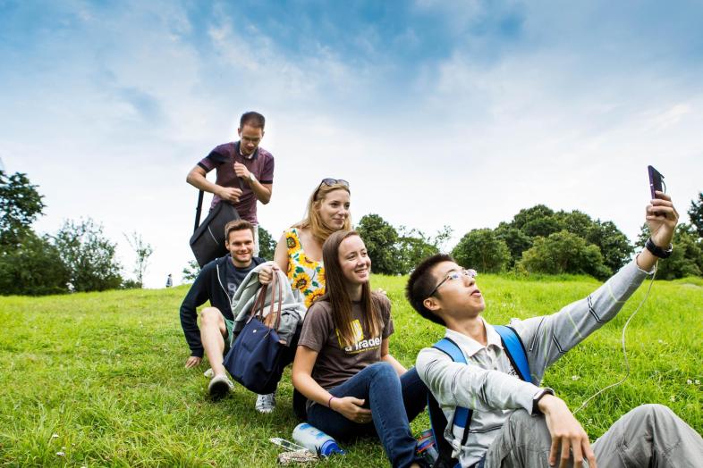 A group of students taking selfies on the lawn.