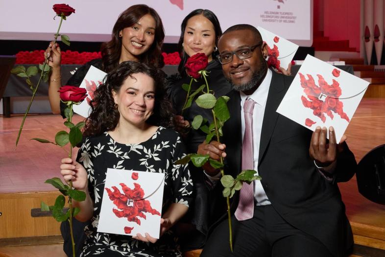 Neljä tuoretta valmistujaa ruusut ja onnittelukirjeet käsissään.