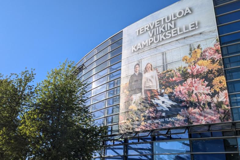 Rakennuksen seinässä lakana, jossa teksti "Tervetuloa Viikin kampukselle!"