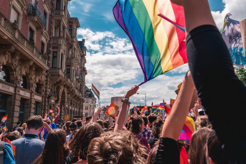 Rainbow flags wave in a parade.