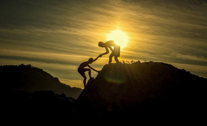 A person helping another person to climb to mountain