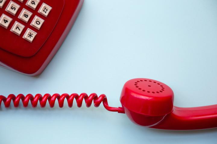 En röd telefon på en vit yta.