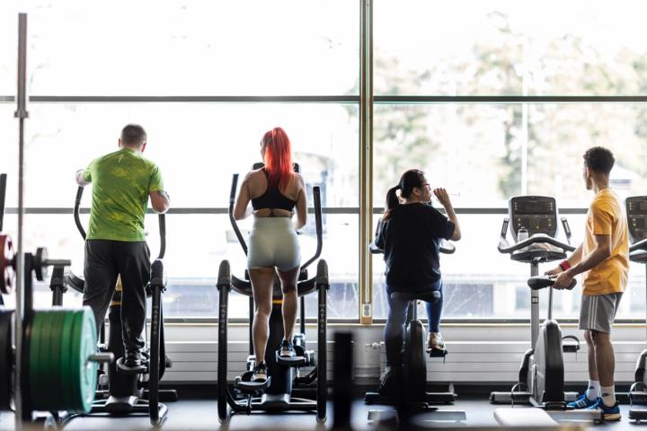 Four persons excersizing at a gym.